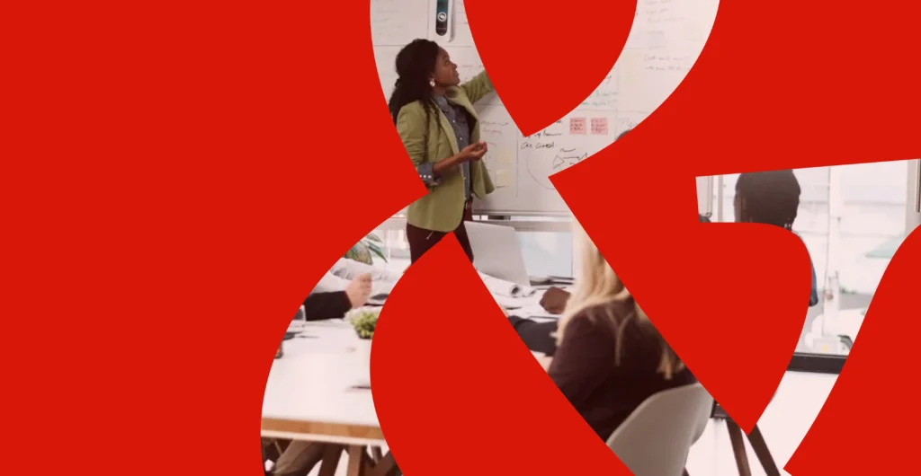 A female marketing director presents a 30-60-90 day marketing plan to a team in a conference room.